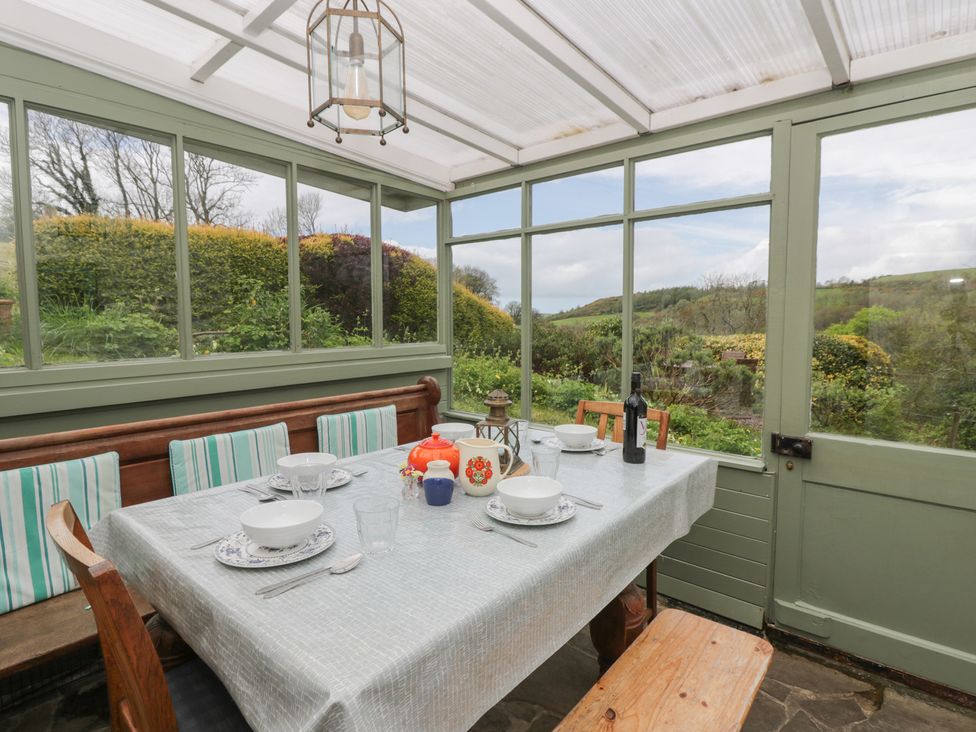 A conservatory with a table set for dining at Tyn Y Fron Brynherbert near Llanrhystud