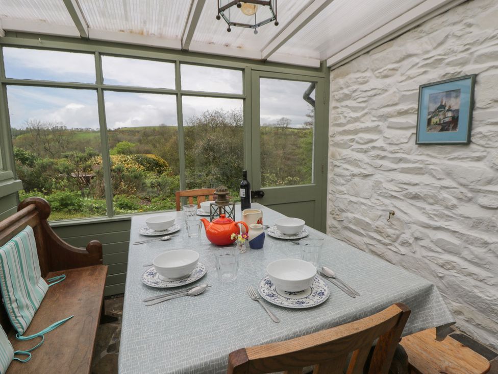 A conservatory with a dining table set at Tyn Y Fron in Brynherbert near Llanrhystud