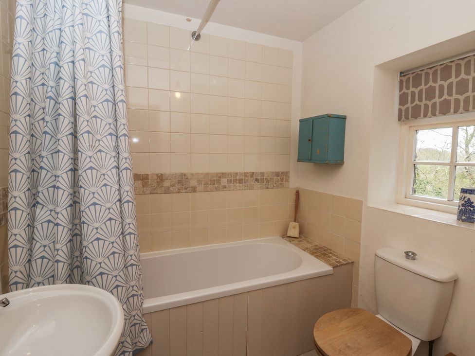 A bathroom with a bathtub, toilet, and window at Tyn Y Fron Brynherbert near Llanrhystud