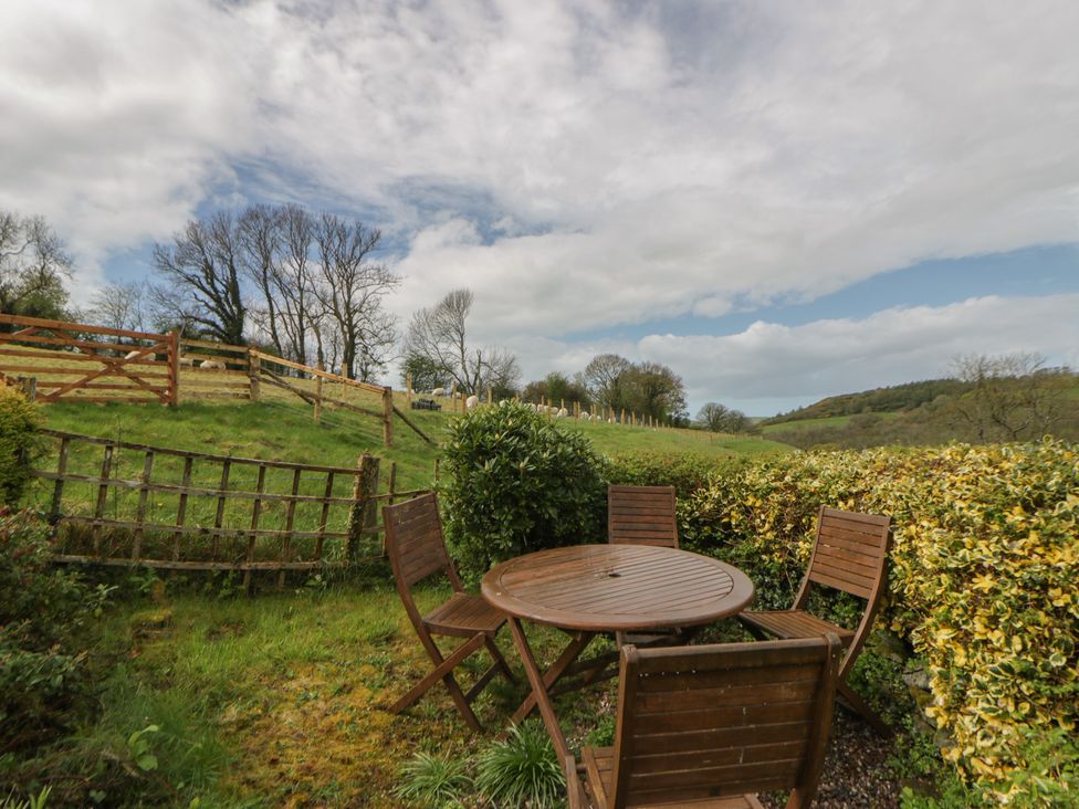 A garden with a wooden table and chairs at Tyn Y Fron Brynherbert near Llanrhystud