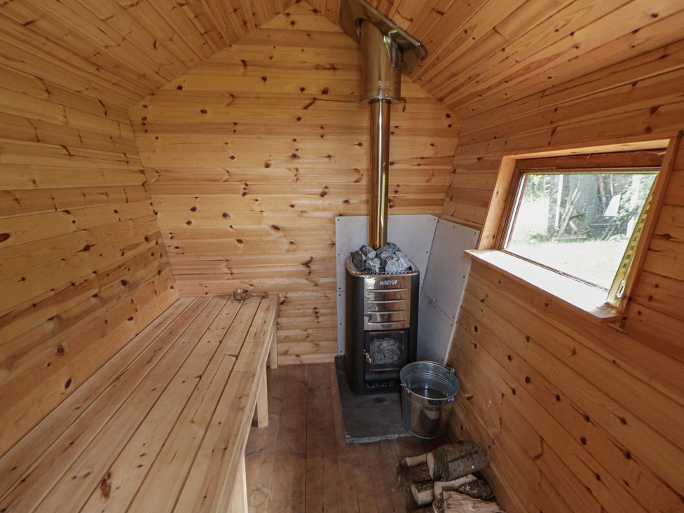 A sauna with a wood stove and benches at Tyn Y Fron in Brynherbert near Llanrhystud