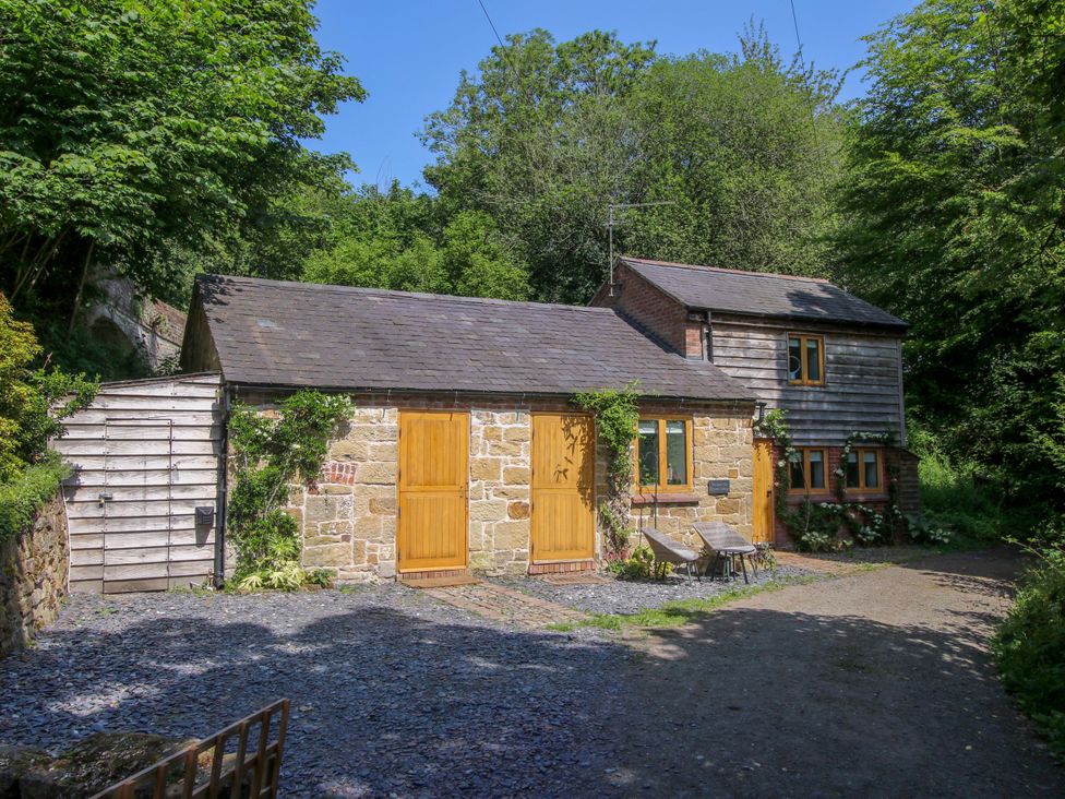 A cottage with wooden door and stone wall at The Lime Kiln Keepers Cottage in Ellesmere