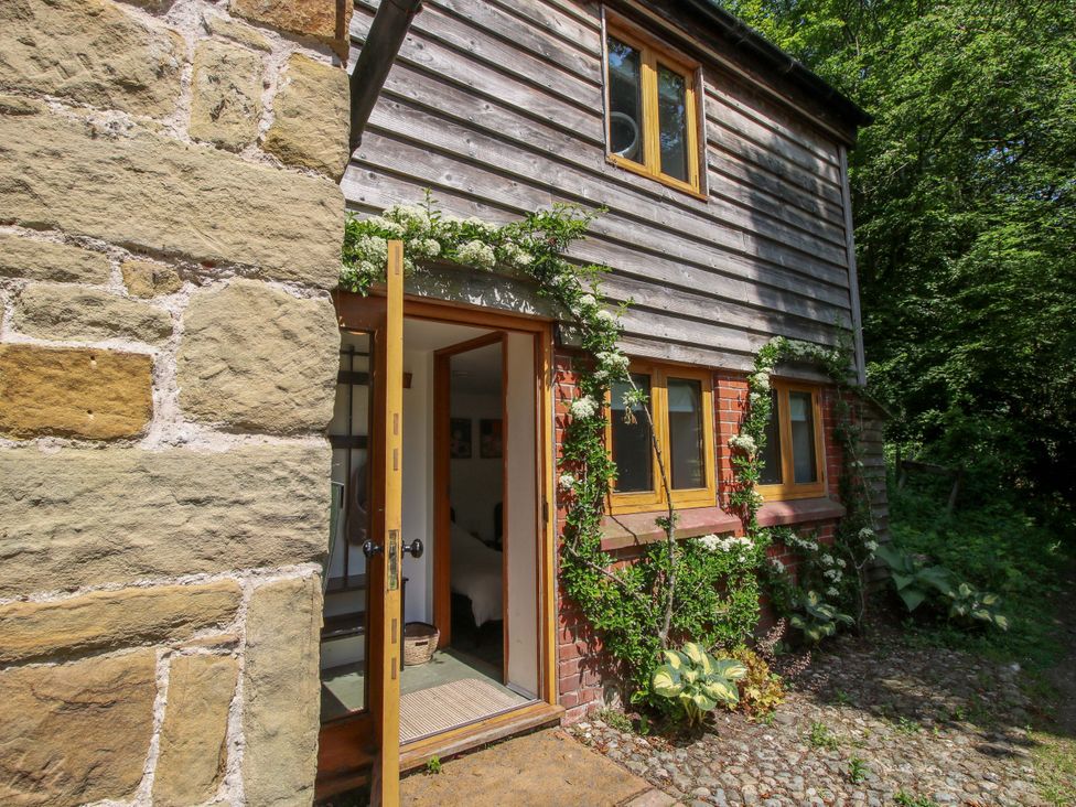 An entrance of a cottage with a stone wall and wooden features at The Lime Kiln Keepers Cottage Ellesmere