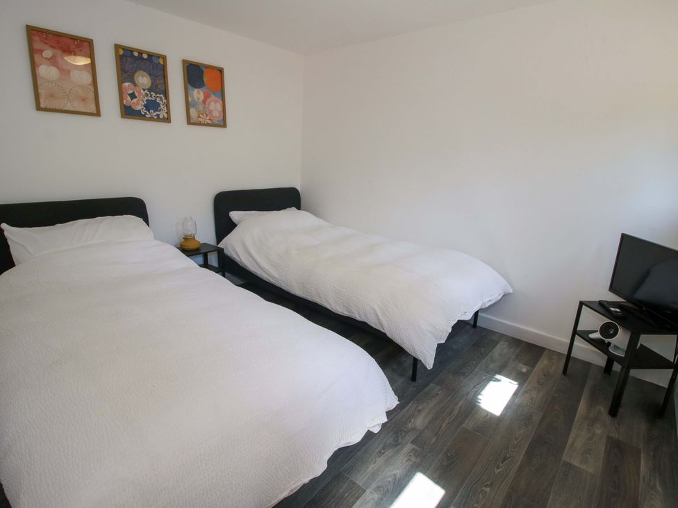 A bedroom with two beds and a television at The Lime Kiln Keepers Cottage in Ellesmere