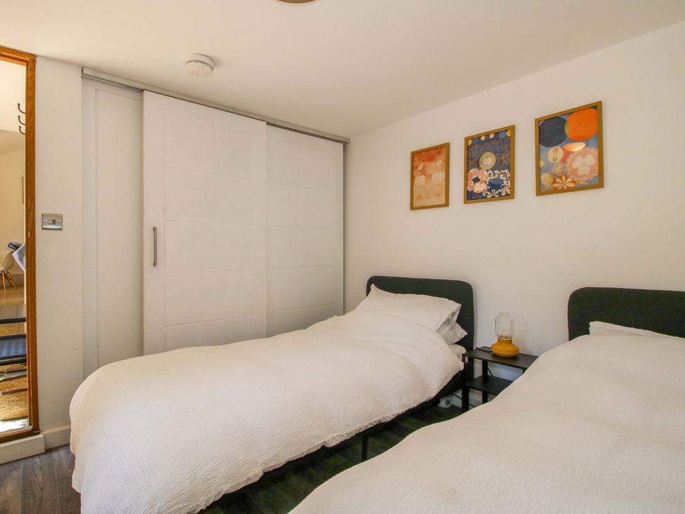 A bedroom with two beds and artwork on the wall at The Lime Kiln Keepers Cottage in Ellesmere