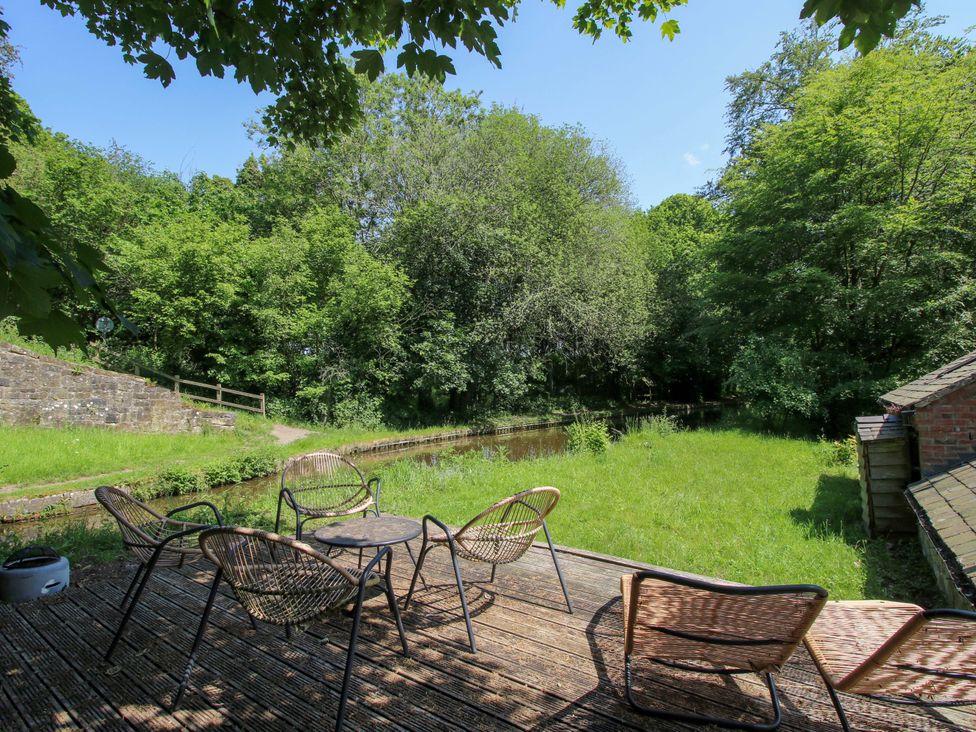 Outdoor seating area with chairs and table near water at The Lime Kiln Keepers Cottage in Ellesmere
