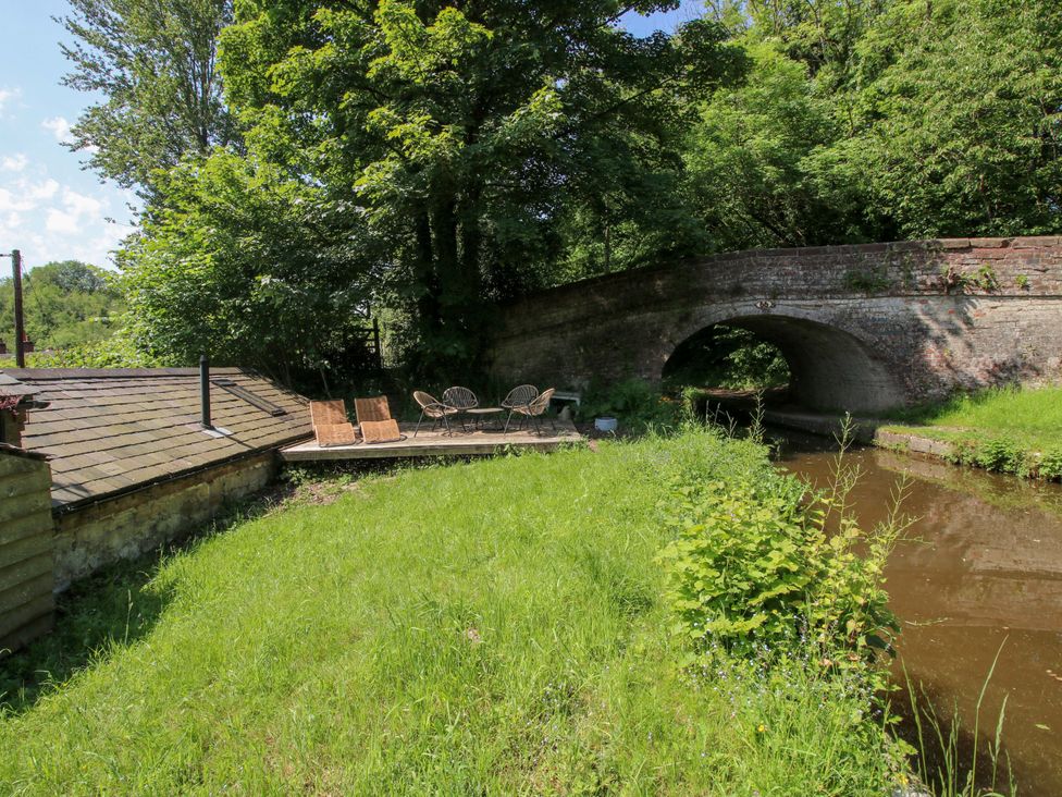 An outdoor area with a bridge and seating by the water at The Lime Kiln Keepers Cottage in Ellesmere