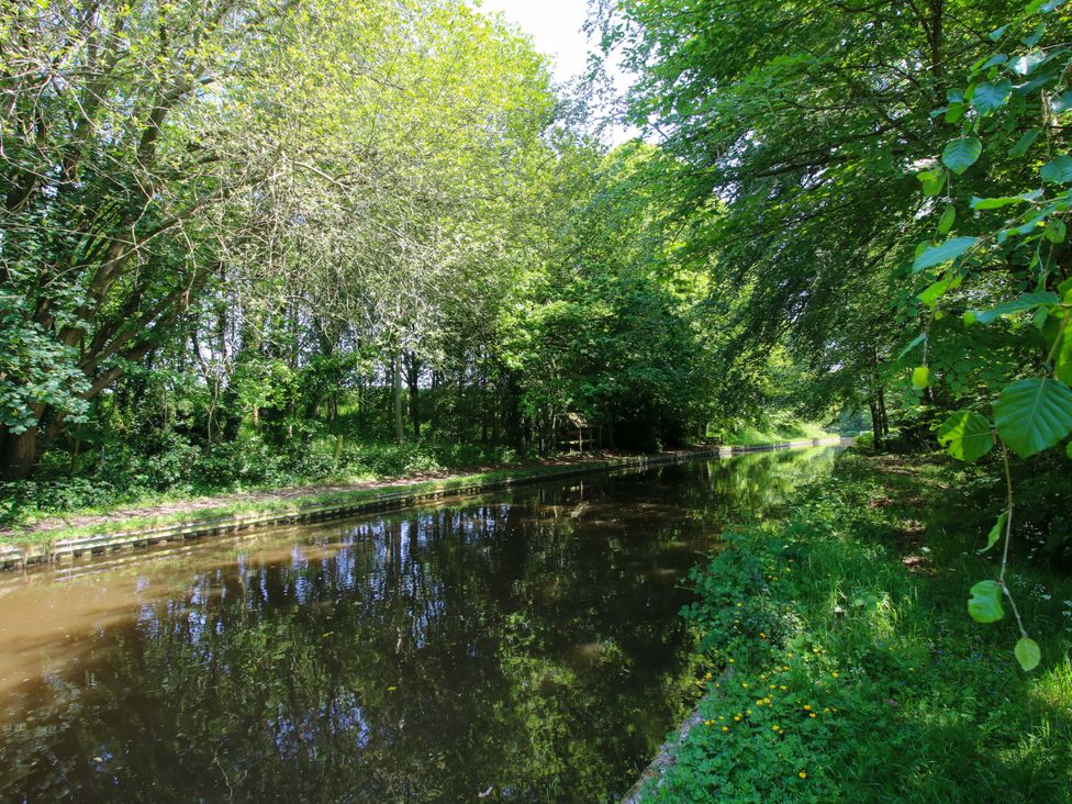 A canal surrounded by trees and grass at The Lime Kiln Keepers Cottage in Ellesmere