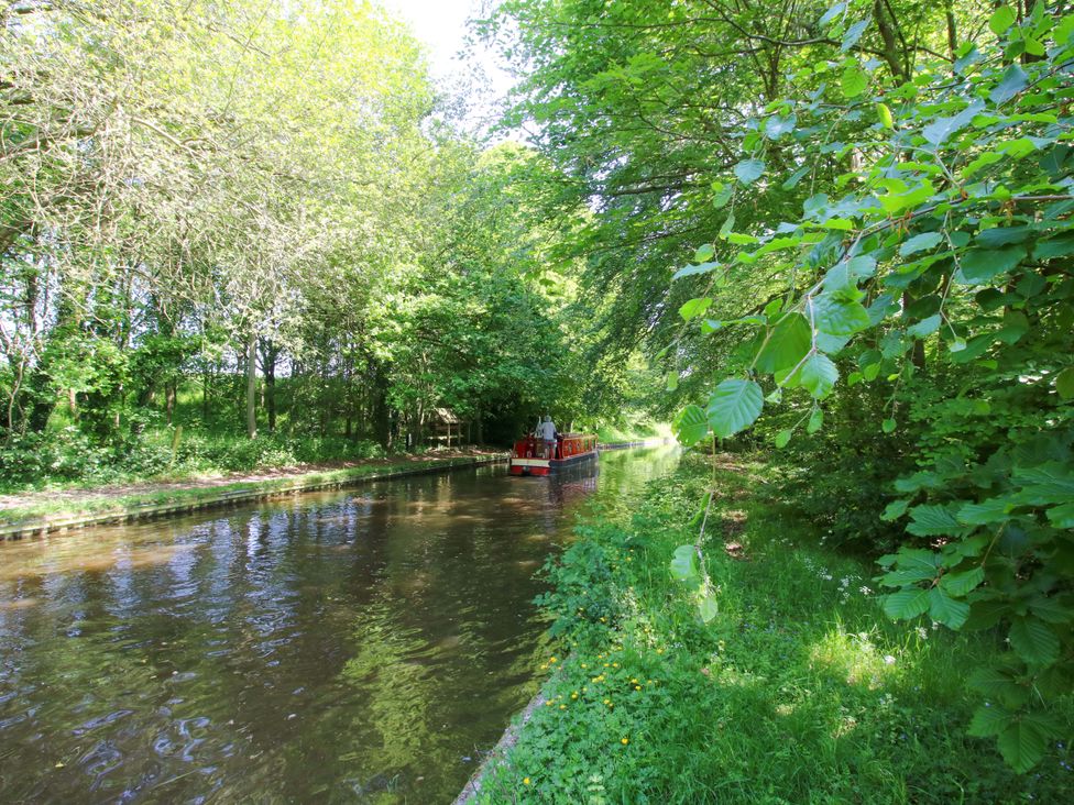 A boat on a canal surrounded by trees at The Lime Kiln Keepers Cottage in Ellesmere