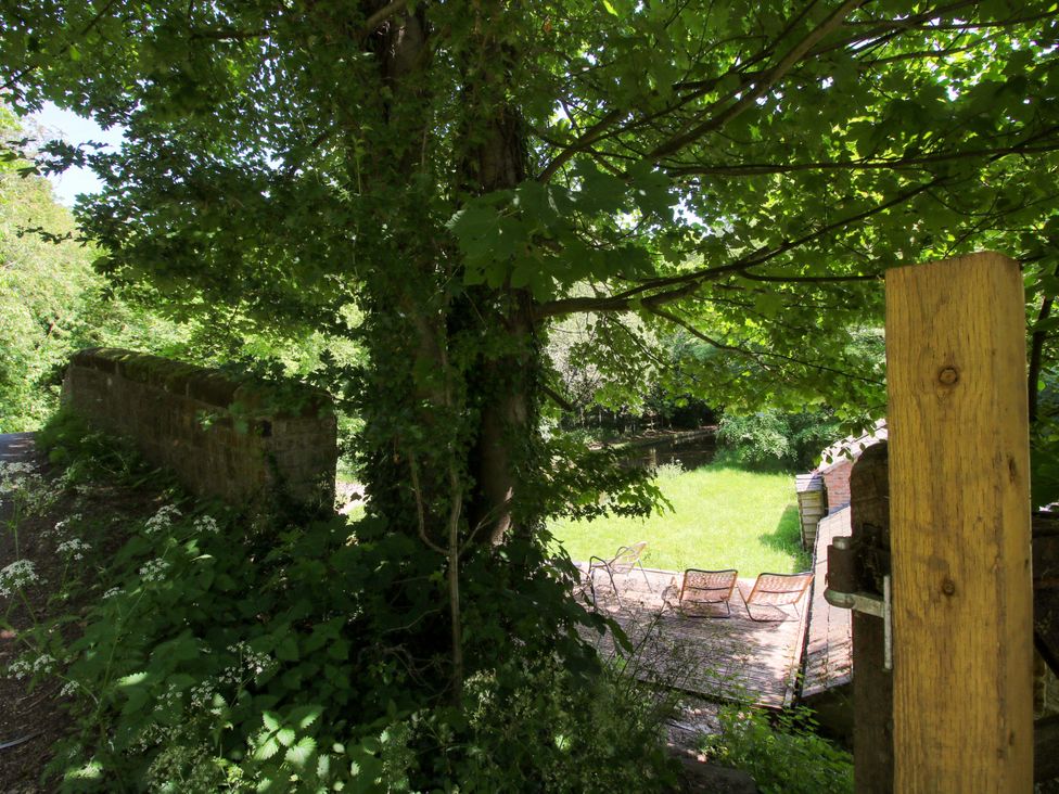 A garden with chairs and a stone wall at The Lime Kiln Keepers Cottage in Ellesmere