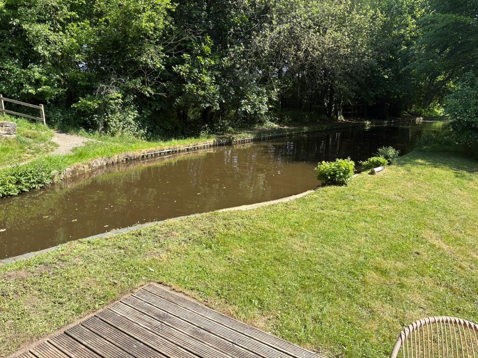 A river beside grass and bushes in a garden at The Lime Kiln Keepers Cottage in Ellesmere