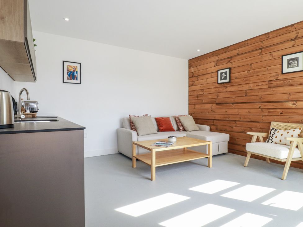 A living room with a sofa and a coffee table at Teach Tra East in Perranporth