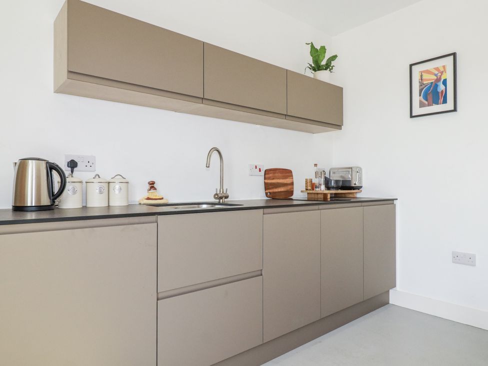 A kitchen with cabinets and appliances at Teach Tra East Perranporth