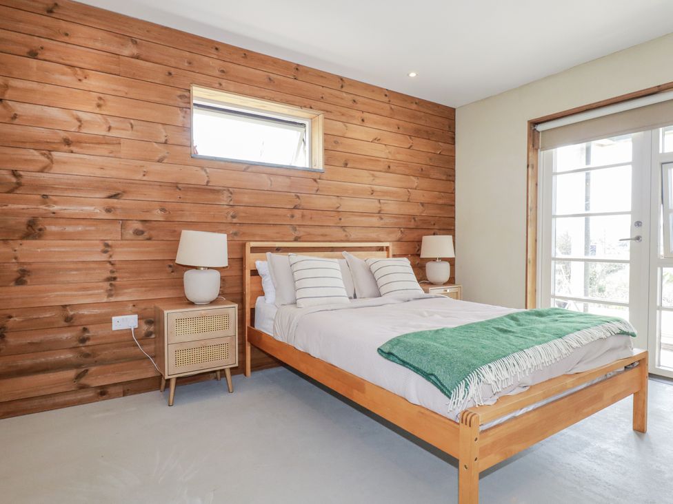 A bedroom with a bed and bedside tables at Teach Tra East Perranporth