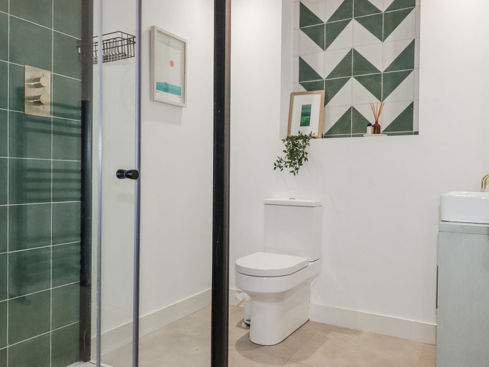A bathroom with a shower, toilet, and sink at Teach Tra East in Perranporth