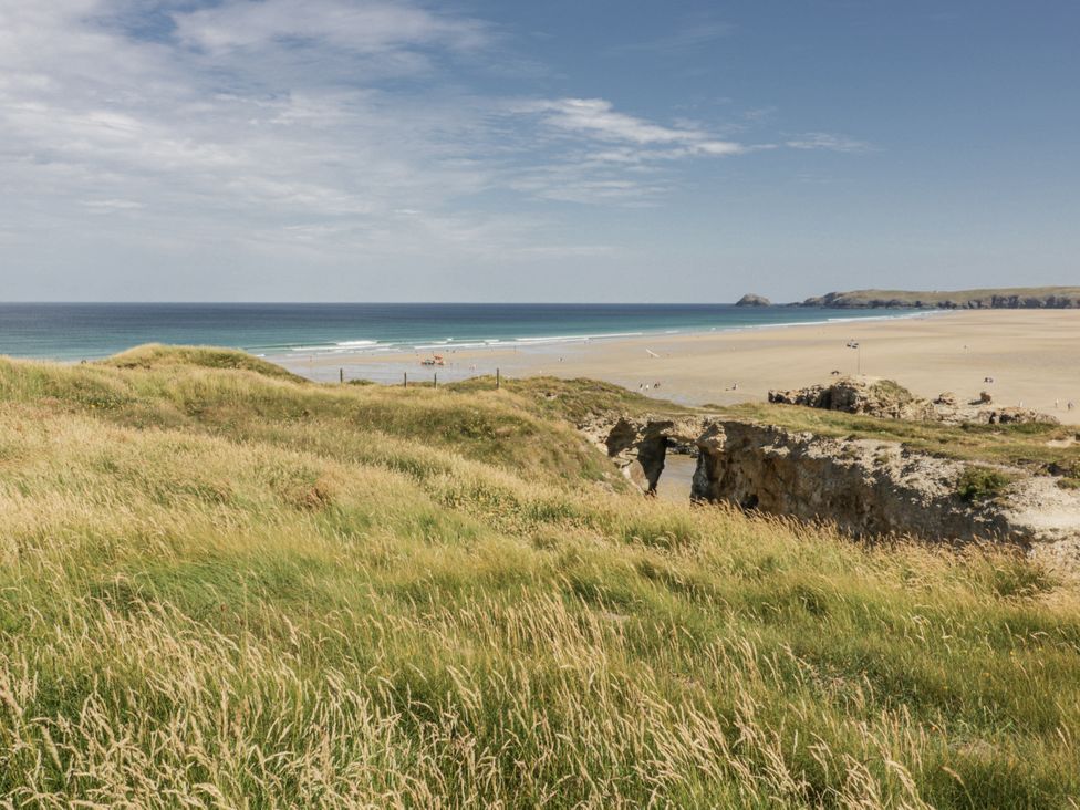 View of the beach and ocean with grass and rocks at Teach Tra East in Perranporth