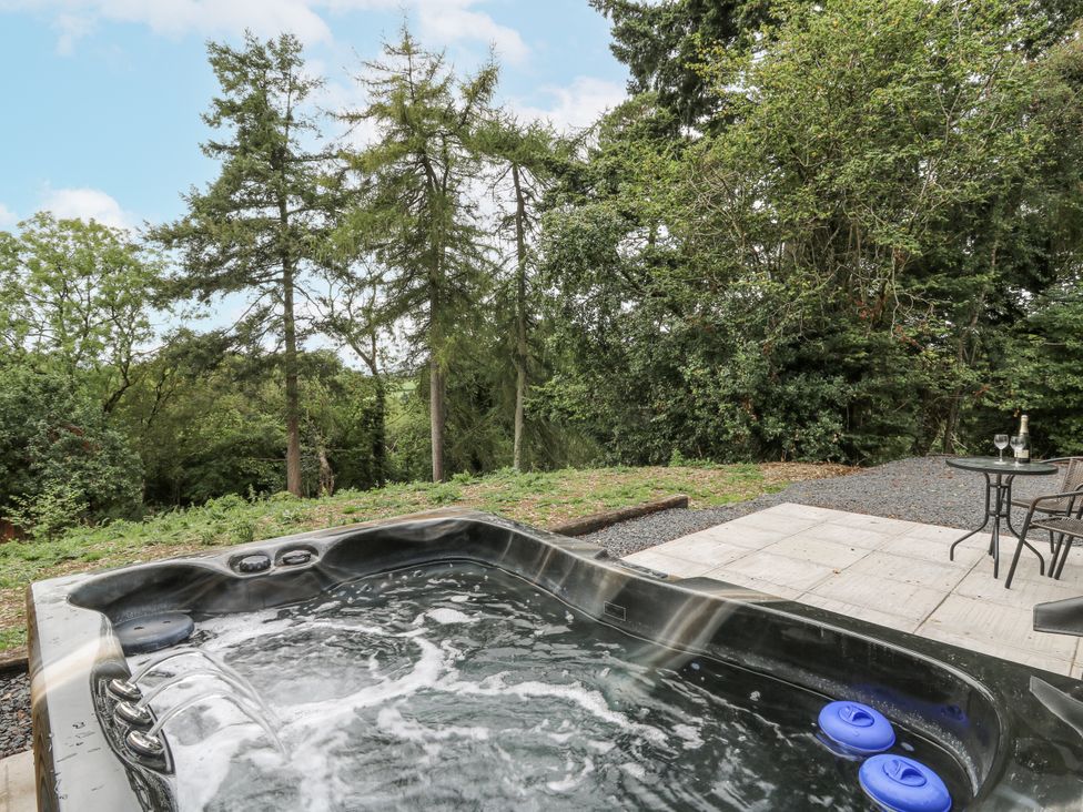 A hot tub and seating area in an outdoor space at Oak View in Rhayader