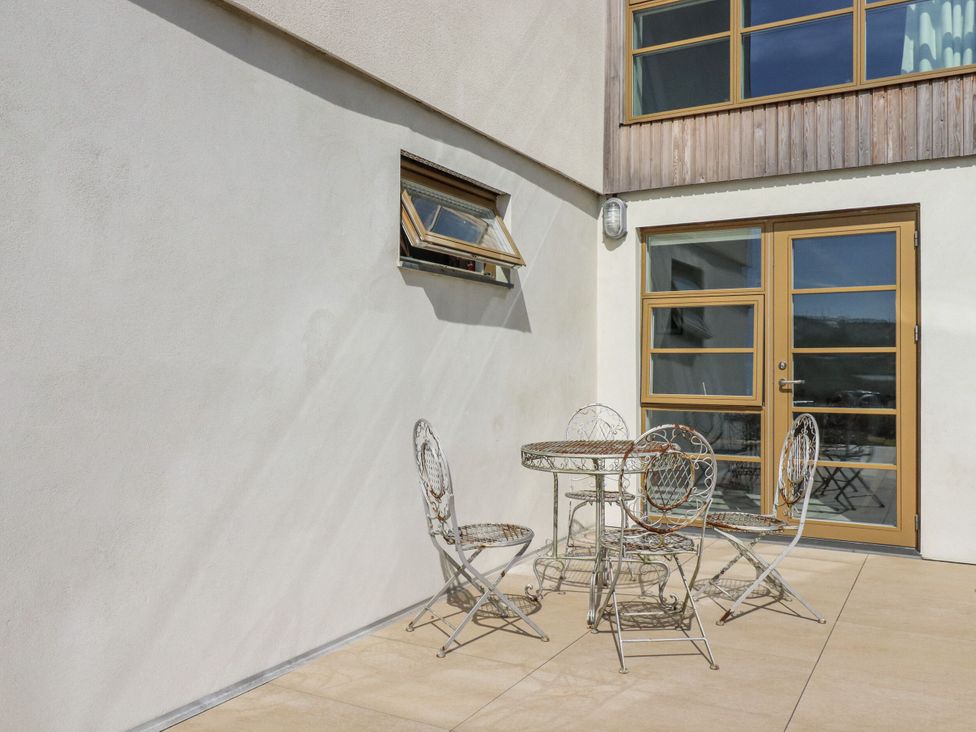 An outdoor patio with a table and chairs at Teach Tra West Perranporth