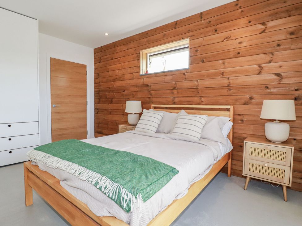 A bedroom with a bed and a window at Teach Tra West in Perranporth