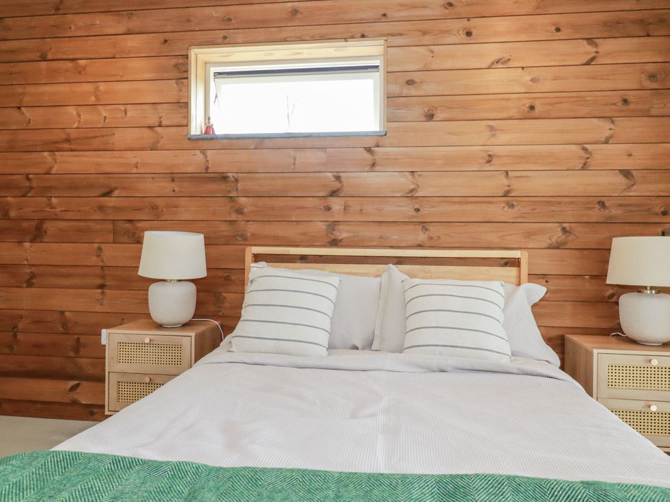 A bedroom with a bed and lamps at Teach Tra West in Perranporth