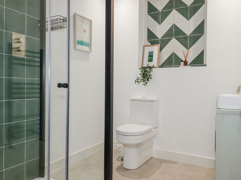 A bathroom with a shower, toilet, and sink at Teach Tra West in Perranporth