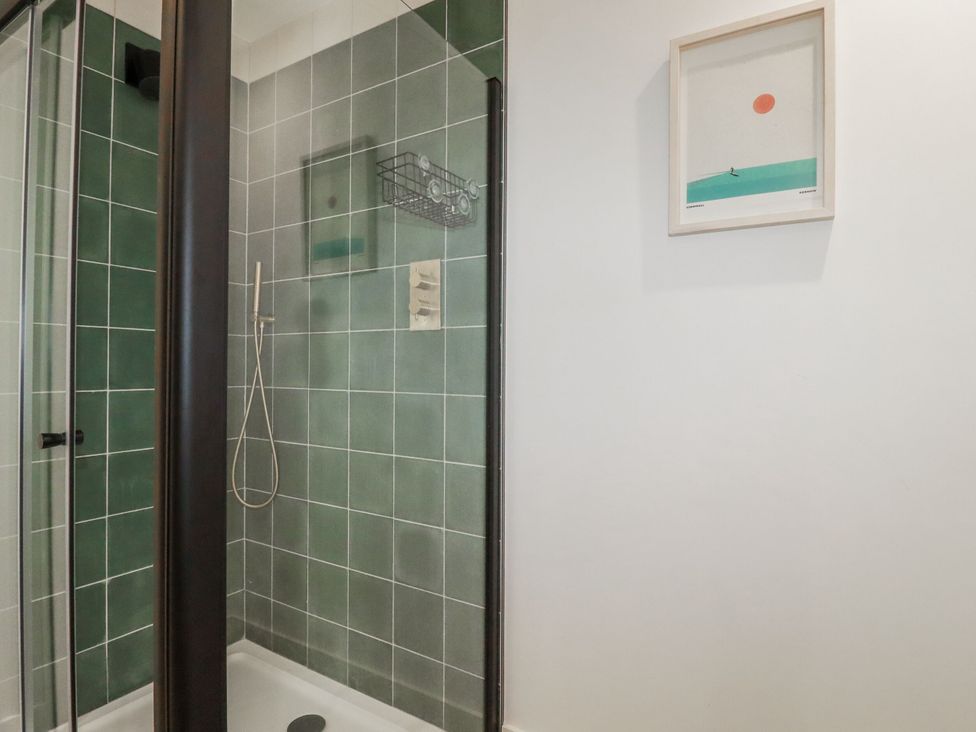 A bathroom with a shower and artwork at Teach Tra West in Perranporth