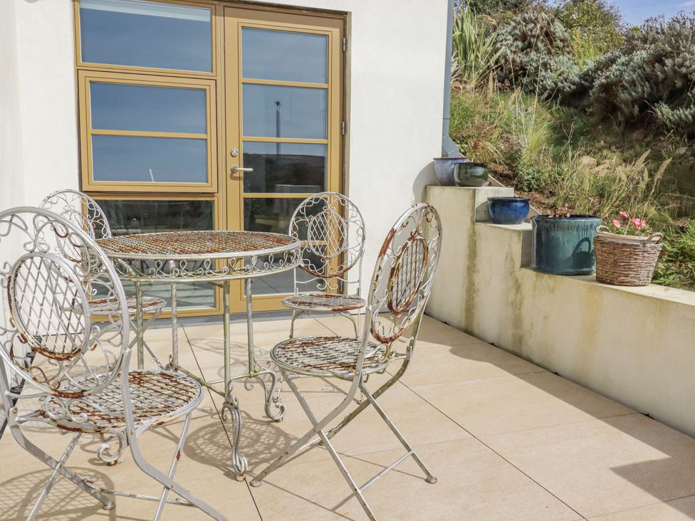An outdoor patio with a table and chairs at Teach Tra West in Perranporth