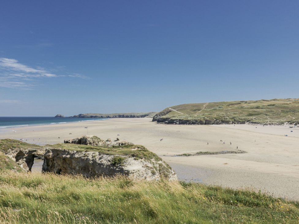 A beach view with grass and rocks at Teach Tra West Perranporth