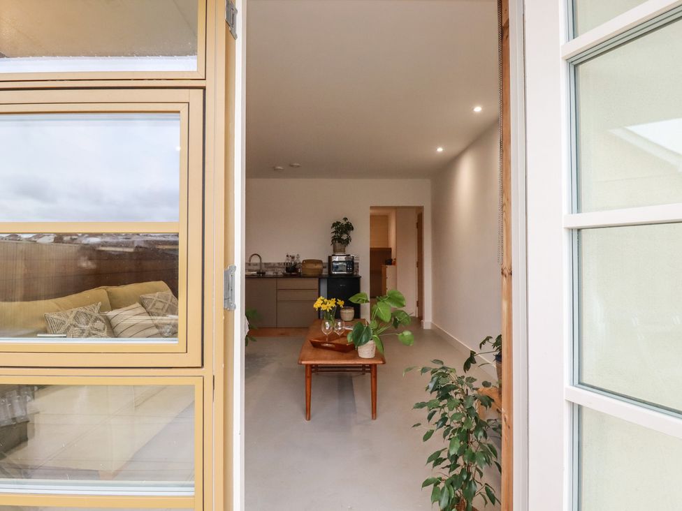 A kitchen with a couch and plants at Teach Tra West in Perranporth