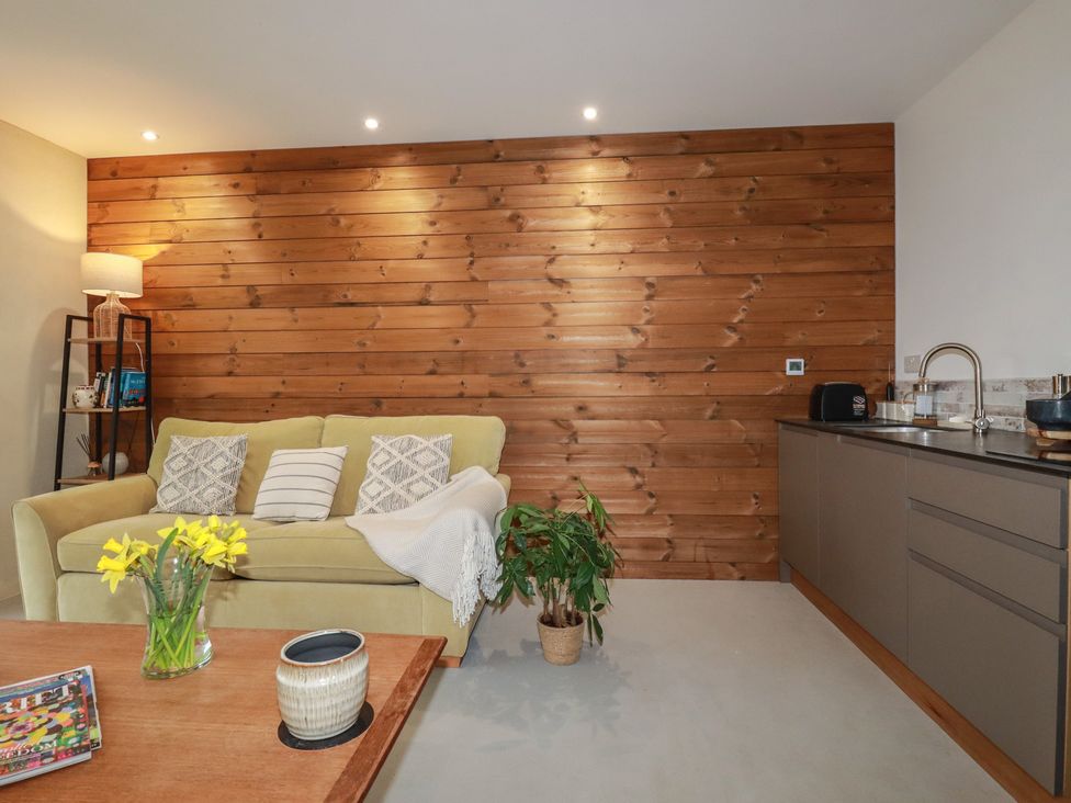 A living room with a sofa, table, and plant at Teach Tra West in Perranporth