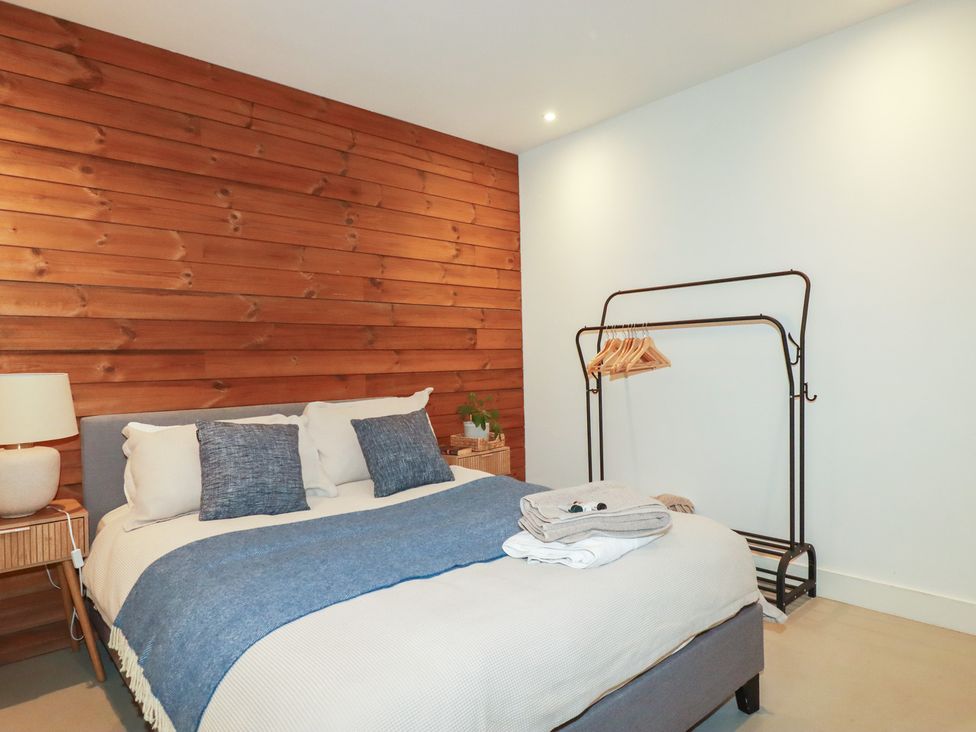 A bedroom with a bed and a hanger rack at Teach Tra West, Perranporth
