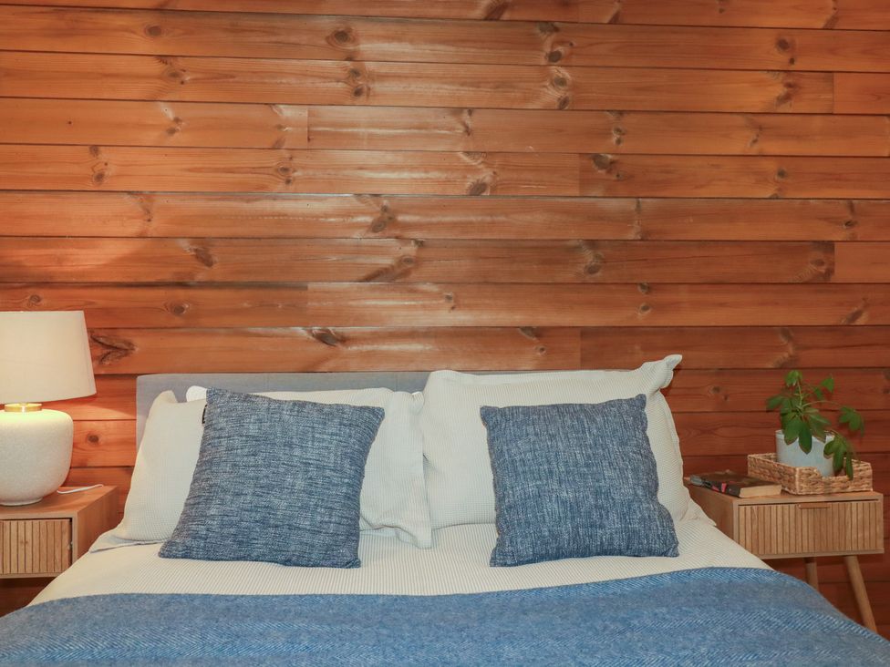 A bedroom with a bed and nightstand at Teach Tra West, Perranporth