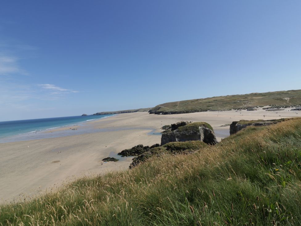 A beach with water and grass at Teach Tra West in Perranporth