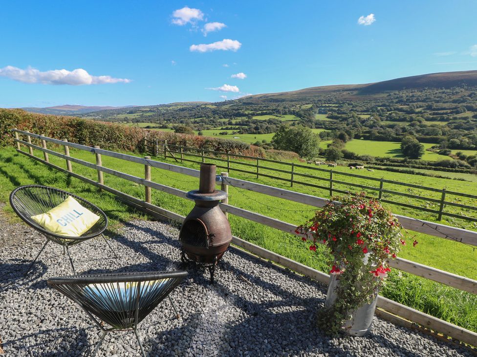 An outdoor seating area with a fire pit and flower pot at Sychnant Farm Retreat Llanedi near Pontarddulais