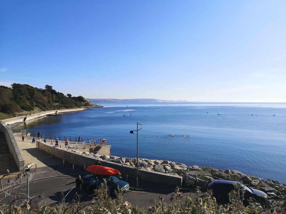 A view of the ocean and shore with people and vehicles at Harbour Heights in Weymouth
