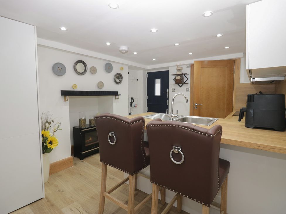 A kitchen with bar stools and a fireplace at Park View Studio in Ambleside