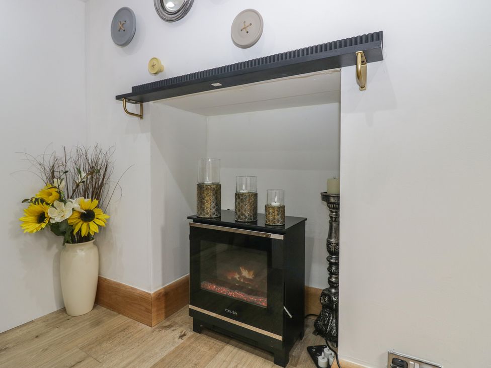 A snug with an electric fireplace and flowers at Park View Studio in Ambleside