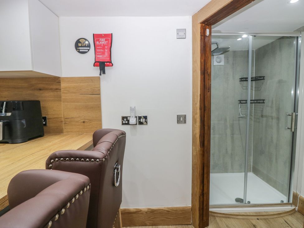 A kitchen with a chair and shower area at Park View Studio in Ambleside