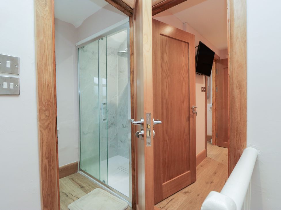 A bathroom with a glass shower and wooden doors at Park View in Ambleside