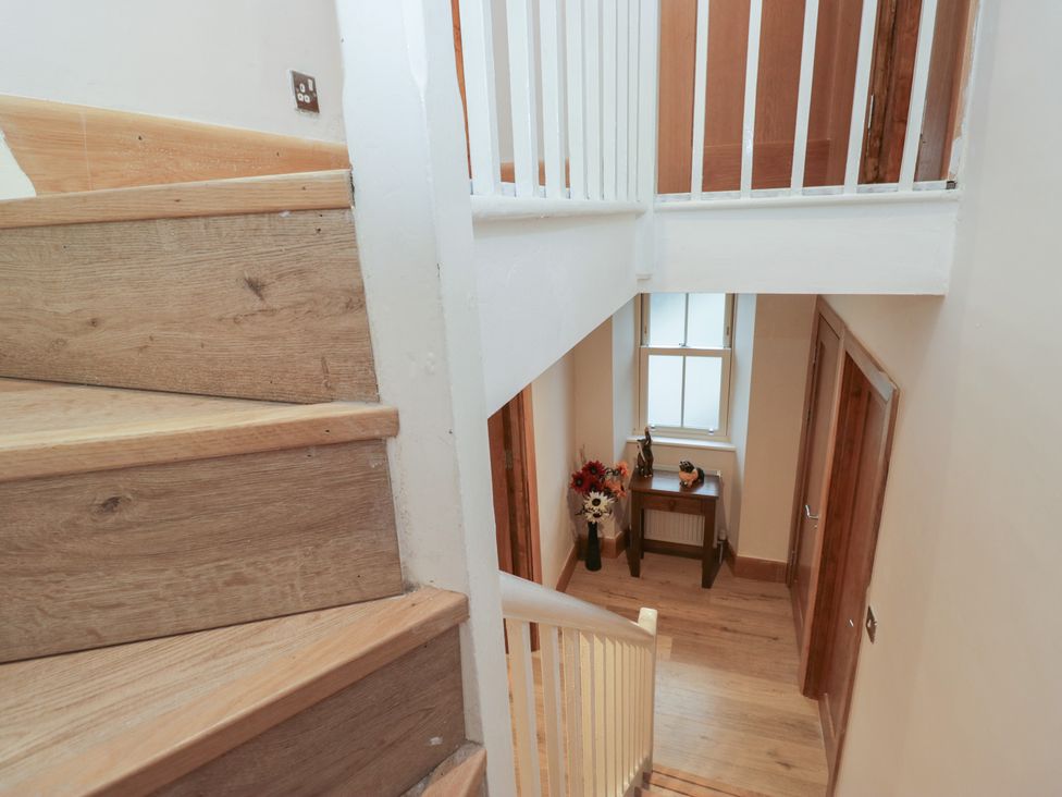 A staircase leading to a hallway with a table and window at Park View in Ambleside