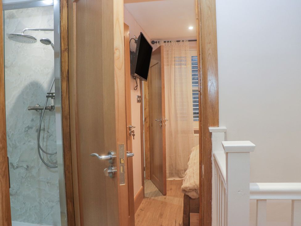 A bathroom with a shower and television at Park View in Ambleside
