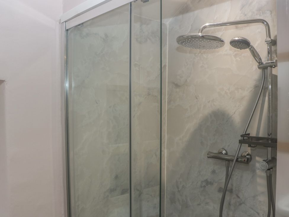 A shower area with a glass door and marble wall at Park View in Ambleside