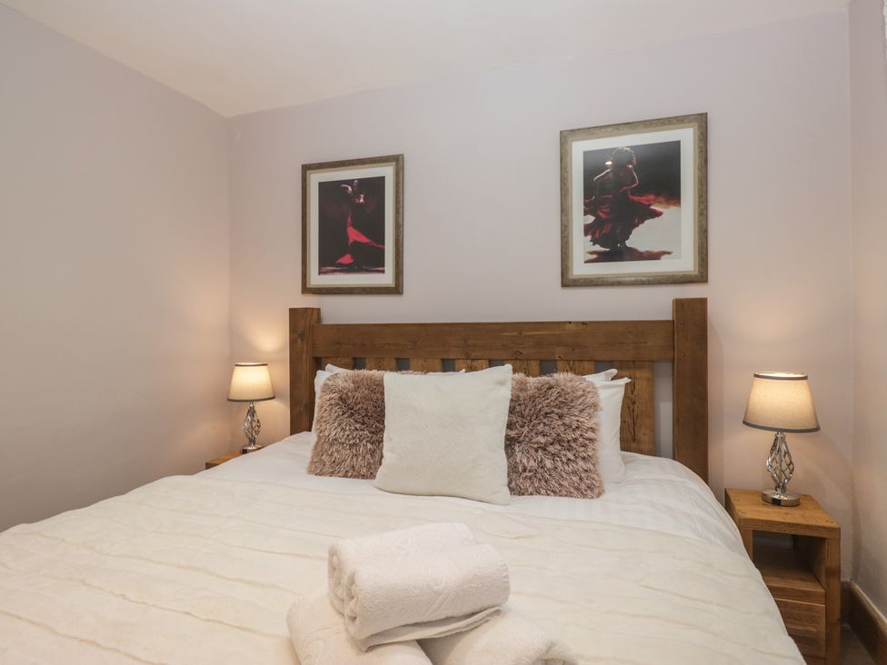 A bedroom with a wooden bed and framed pictures at Park View in Ambleside