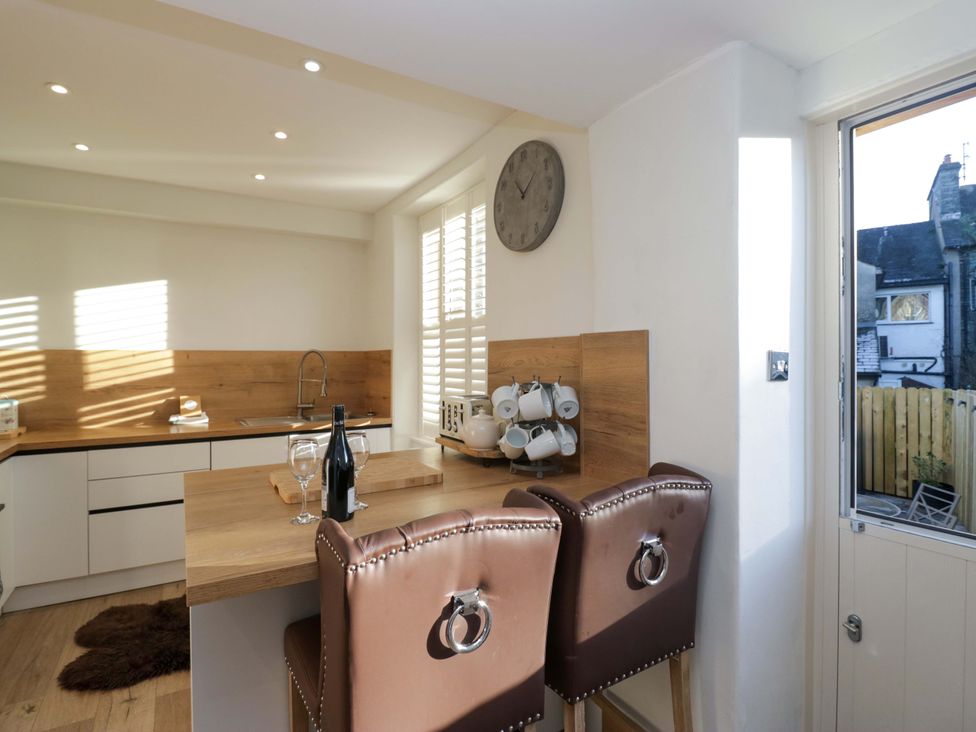 A kitchen with bar stools and wine bottles at Park View in Ambleside
