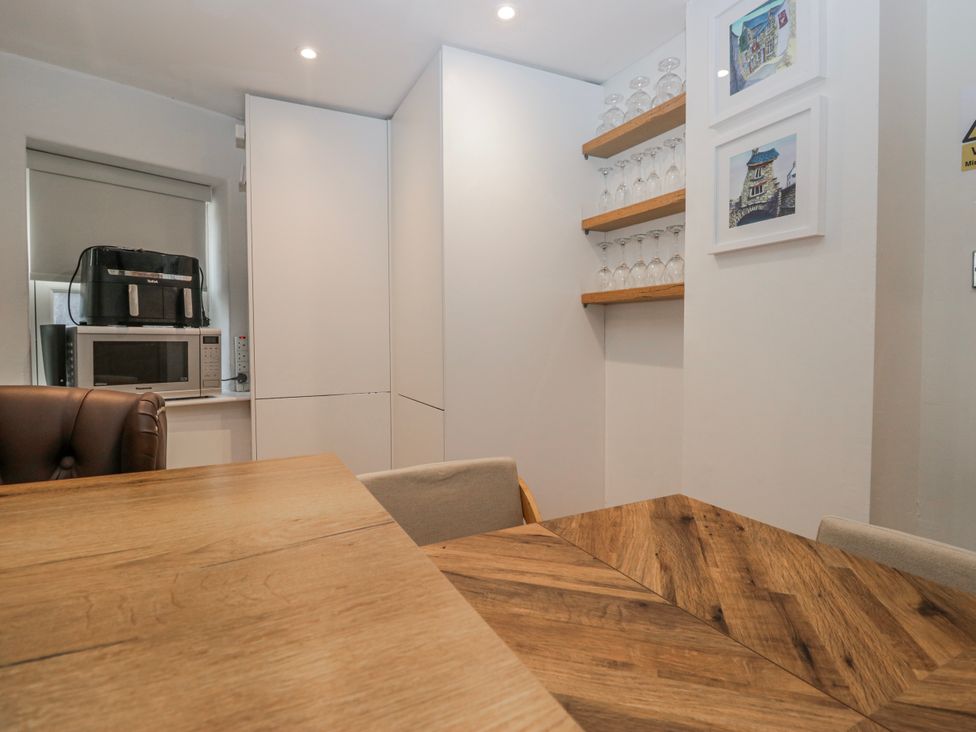 A dining room with a table and shelves holding glassware at Park View in Ambleside