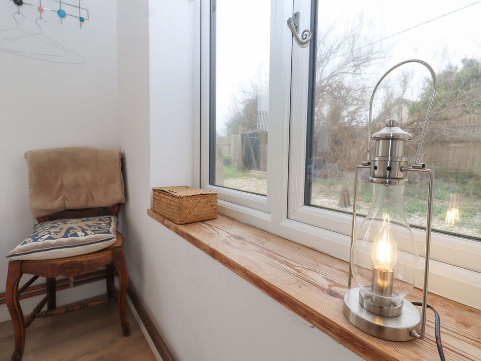 A corner with a chair, cushion, basket, and lamp at Greengates in Rye