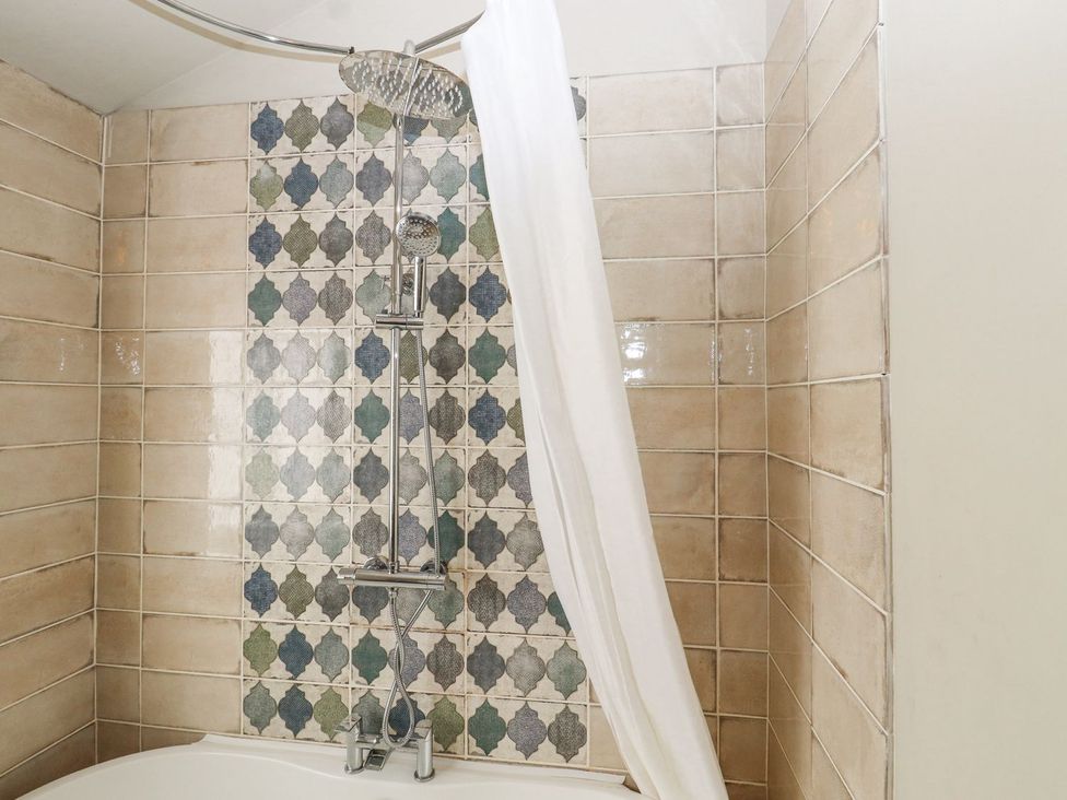 A shower with tiles and curtain in a bathroom at Greengates in Rye