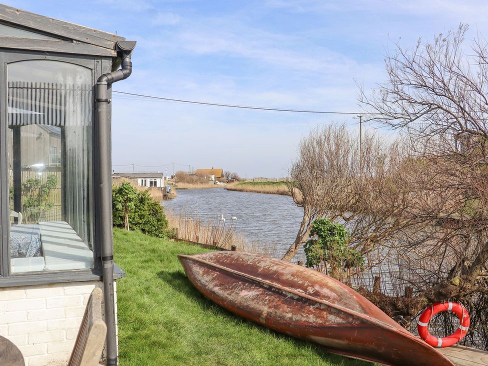 An outdoor view of a river with a canoe and a glass structure at Greengates in Rye