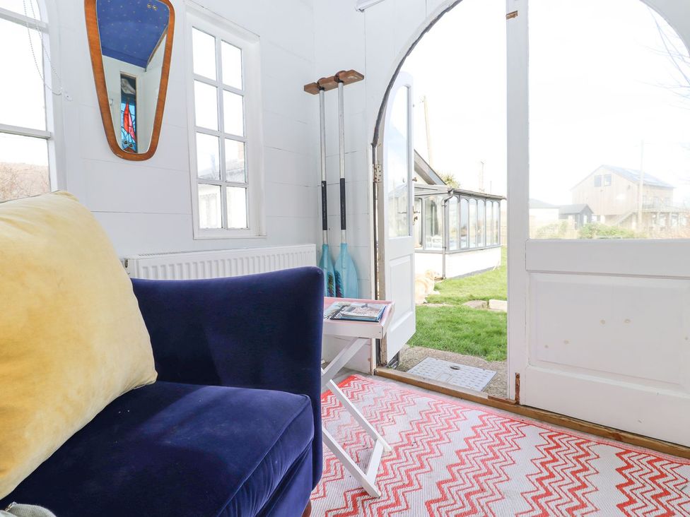 A snug with a blue sofa and a door leading to the garden at Greengates in Rye