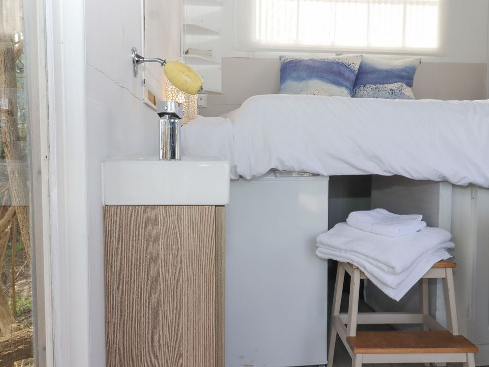 A bedroom with a bed, towels, sink and fridge at Greengates in Rye